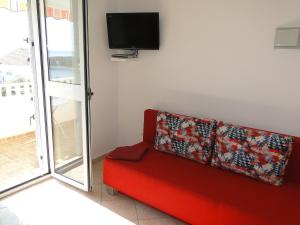 a red couch sitting in a room with a tv at Zele in Dolac