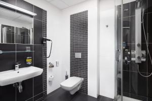 a bathroom with a sink and a toilet and a shower at Hotel Nikolas in Ostrava
