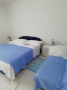 two beds in a white room with blue sheets at Apartment Villa Bajna in Živogošće