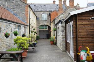 um beco entre dois edifícios com mesas e bancos em No. 2 Smith Cottages em Langport