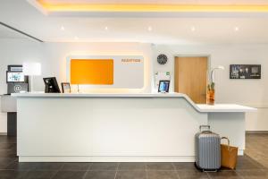 a lobby with a counter with a suitcase in front of it at ibis budget Aachen City in Aachen