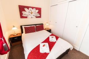 a bedroom with a white bed with red pillows at Mycosy Provost Road in Dundee