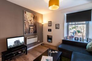 a living room with a couch and a tv at Mycosyapartments54 in Paisley