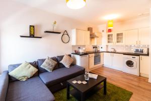 a living room with a couch and a kitchen at Mycosyapartments54 in Paisley