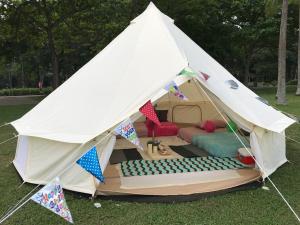 une tente blanche avec un lit dans l'herbe dans l'établissement Glamping Kaki - Large Bell Tent, à Singapour