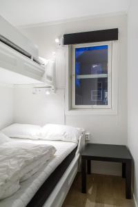 a white bedroom with a bed and a window at Hafjell Alpinlandsby Pluss in Hafjell