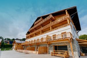 - un bâtiment avec des balcons en bois sur le côté dans l'établissement TERRESENS - Les Fermes du Mont-Blanc, à Combloux