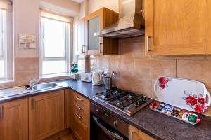 a kitchen with wooden cabinets and a stove top oven at Mycosyapartment 47 in Paisley