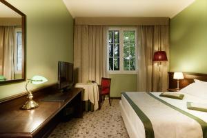 ボローニャにあるMeditur Hotel Bolognaのベッド、デスク、テレビが備わるホテルルームです。