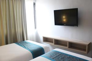 a hotel room with two beds and a flat screen tv at Sahid Mutiara Karawaci in Tangerang