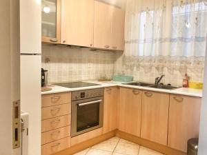 a small kitchen with wooden cabinets and a sink at Seaview 2nd flr. apt. next to the beach, wifi,a/c,p/c media. in Anavissos