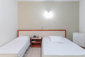 two beds in a room with a nightstand between them at Hotel Princeton in Piracicaba
