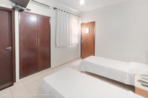 a bedroom with two beds and a closet at Hotel Princeton in Piracicaba