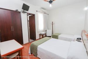 a bedroom with two beds and a tv on the wall at Hotel Princeton in Piracicaba