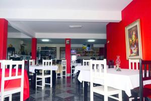 a dining room with white tables and red walls at Hotel Miramar Fogo Brava in São Filipe