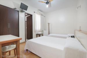a bedroom with two beds and a desk and a tv at Hotel Princeton in Piracicaba