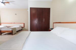 a bedroom with two beds and a wooden door at Hotel Princeton in Piracicaba