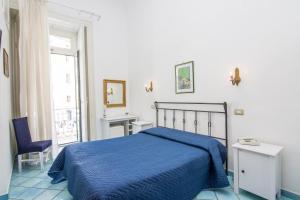 a bedroom with a blue bed and a window at Hotel Fontana in Amalfi