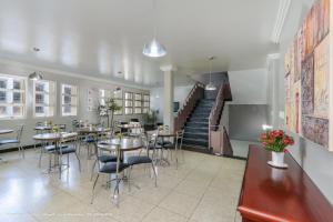 a restaurant with tables and chairs and a staircase at Hotel Princeton in Piracicaba