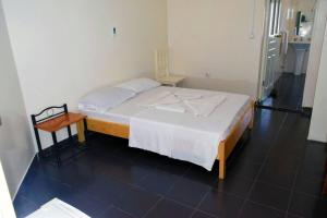 1 dormitorio con 1 cama con colcha blanca y mesa en Hotel Miramar Fogo Brava, en São Filipe