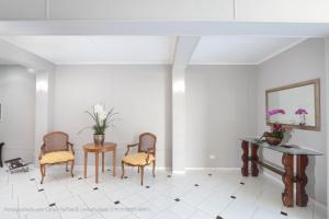 a room with chairs and a table and a mirror at Hotel Princeton in Piracicaba