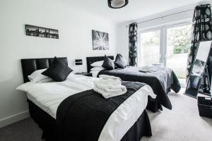 a bedroom with three beds with black and white sheets at Woodlands Luxury 4 Bedroom Townhouse Cults in Aberdeen