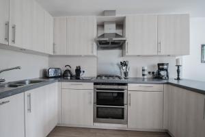 a kitchen with white cabinets and stainless steel appliances at Woodlands Luxury 4 Bedroom Townhouse Cults in Aberdeen