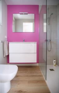 a bathroom with a white toilet and a pink wall at Bellsol Rooms in Pineda de Mar +11 photos