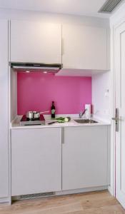 una cocina con armarios blancos y una pared rosa en Bellsol Rooms, en Pineda de Mar