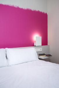 Un dormitorio con una pared rosa y una cama blanca en Bellsol Rooms en Pineda de Mar
