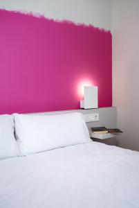 una camera da letto con una parete rosa e un letto bianco di Bellsol Rooms a Pineda de Mar