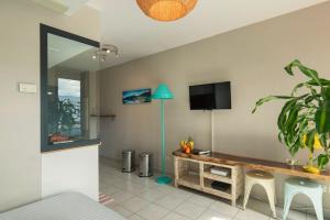 a living room with a table and a flat screen tv at Ti Macoua Studio bord de mer in Saint-Pierre