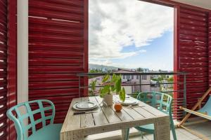 a wooden table and chairs on a balcony with a view at Ti Macoua Studio bord de mer in Saint-Pierre