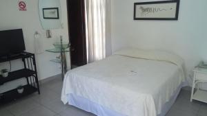 um pequeno quarto com uma cama e uma televisão em Apart Hotel Turey em Santo Domingo