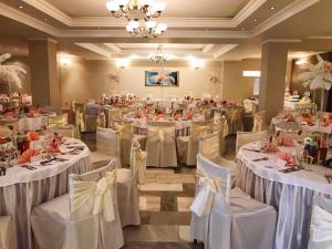 un salón de banquetes con mesas y sillas blancas en Hotel Merkur en Kaluža