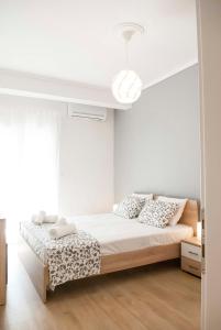 a white bedroom with a bed with two pillows at Cataleya Thessaloniki - Urban Stay in Thessaloniki