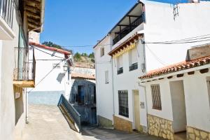 an alley with white buildings and the ocean in the background at La CasetA in Puebla de Benifasar