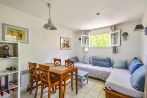 a living room with a table and a couch at Residence Les Grands Pins - maeva Home in Carcans