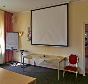 a large projection screen on a wall with a table and a chair at Hotel Schwarzes Ross in Siebenlehn