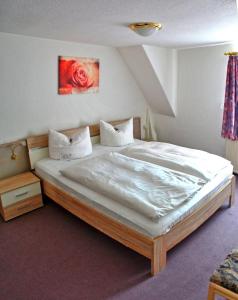 a bedroom with a large bed with white sheets at Hotel Schwarzes Ross in Siebenlehn