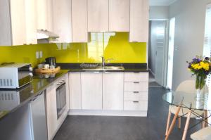 una cocina con armarios blancos y una pared amarilla en Columbine Place, en Durbanville 8 fotos más