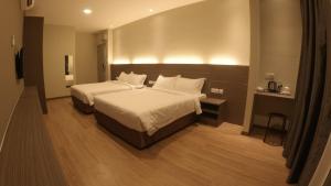 una camera d'albergo con due letti con lenzuola bianche di U Design Hotel Kuala Lipis a Kuala Lipis