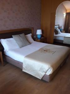 una camera d'albergo con un grande letto bianco e uno specchio di Hotel Motel Visconteo a Binasco