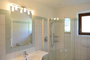 ein Bad mit einem Waschbecken und einer Dusche mit einem Spiegel in der Unterkunft Hotel Sport Robert in Sulden