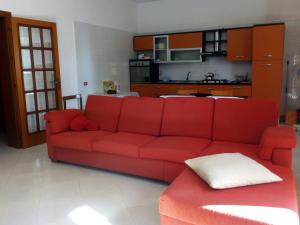 a red couch in a living room with a kitchen at Casa Paradiso in Brindisi