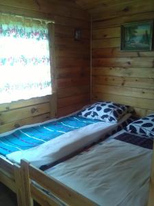 two beds in a log cabin with a window at Domki przy nowej plaży i promenadzie w Mikolajkach in Mikołajki