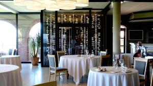 セッラルンガ・ダルバにあるTota Virginia Antico Podereの白いテーブルと椅子、ワインボトルを用意したレストラン