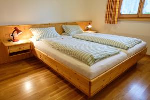 Cama grande de madera en habitación con suelo de madera en Gästehaus Hausberger en Schruns-Tschagguns