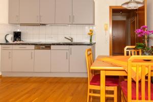 a kitchen with white cabinets and a table with chairs at Gästehaus Hausberger in Schruns