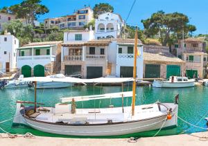 Ein Boot liegt im Wasser in der Nähe der Häuser. in der Unterkunft Marblau Mallorca in Cala Figuera